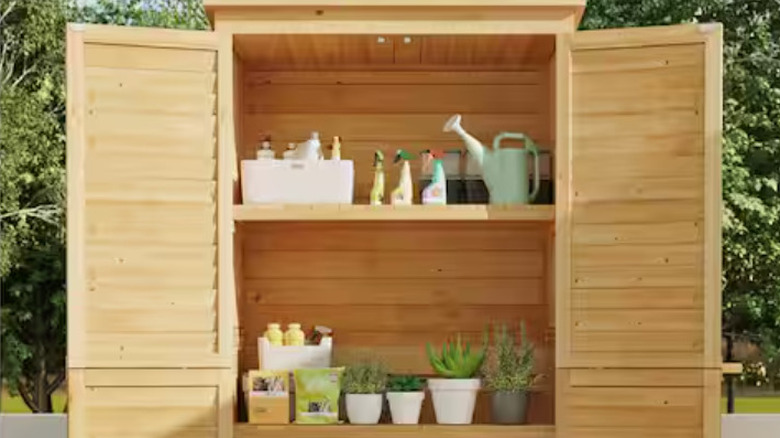 The all natural wood garden shed with interior shelves of plants and supplies.