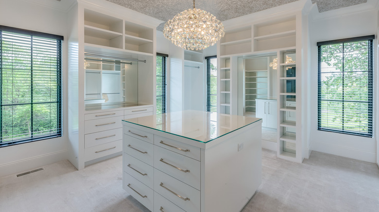 A spacious walk-in closet with a storage island and a chandelier.