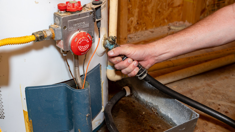 Hose being connected to a water heater to drain it