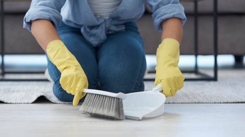 Close-up of a person sweeping with a dustpan and brush