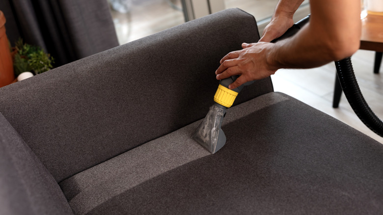 A person using an upholstery cleaner on a sofa