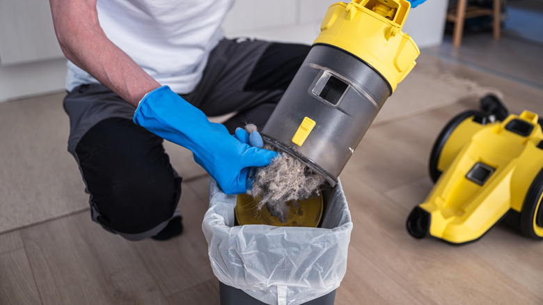 Close-up of a person emptying a vacuum cleaner dust chamber