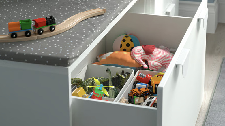 An IKEA SMÅSTAD bench with toy storage drawer, filled with an array of toys