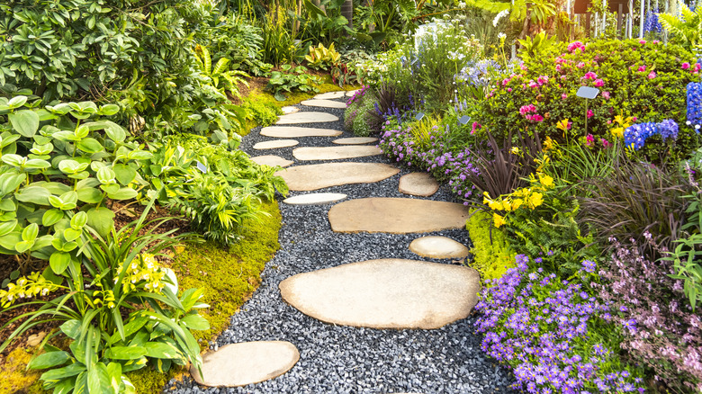 Beautiful stepping stone and gravel pathway winding through a colorful garden