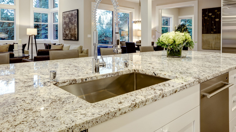A kitchen island with a cream granite countertop with brown flecks