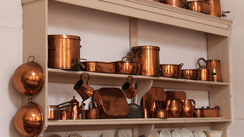 assorted copper cookware on a wall-mounted shelf