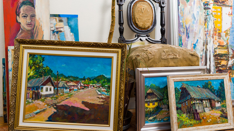 Framed paintings leaning against a threadbare antique chair