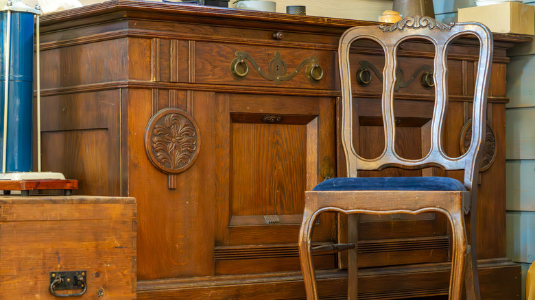 Ornate wooden chair with velvet upholstery in front of wood executive desk.