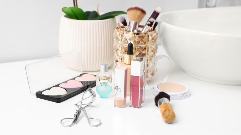 Makeup brush and products strewn about on bathroom countertop