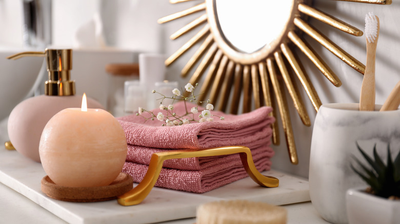 Decorative tray with a large candle burning and towels with flowers on them