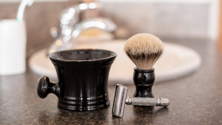 Silver razor and shaving brush on a bathroom counter