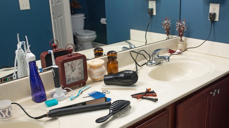 Hair styling tools and care products cluttering up a bathroom counter