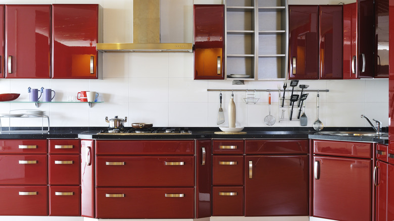 Kitchen with dark red cabinets and gold hardware