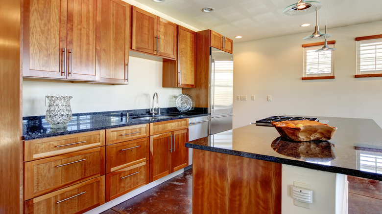 Kitchen with warm brown cabinets and black countertops