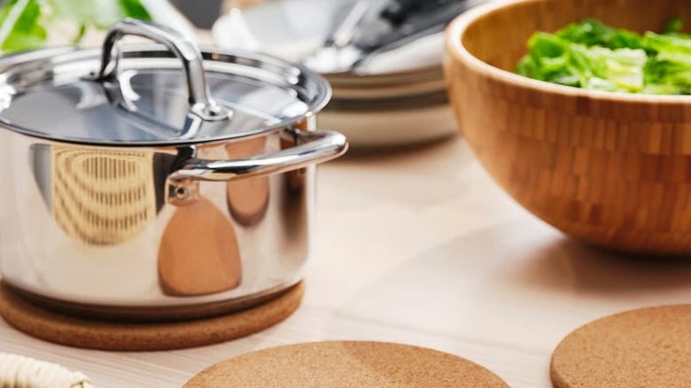 A closed pot over a cork trivet on a kitchen countertop