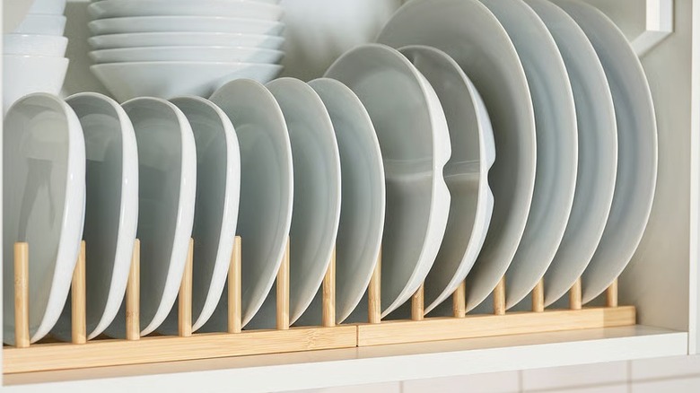 A bamboo plate holder loaded with plates of different sizes