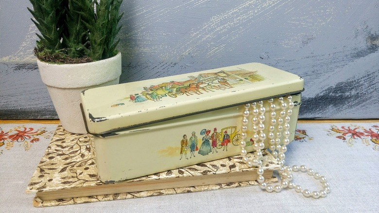 A vintage tea tin with a pearl necklace spilling out