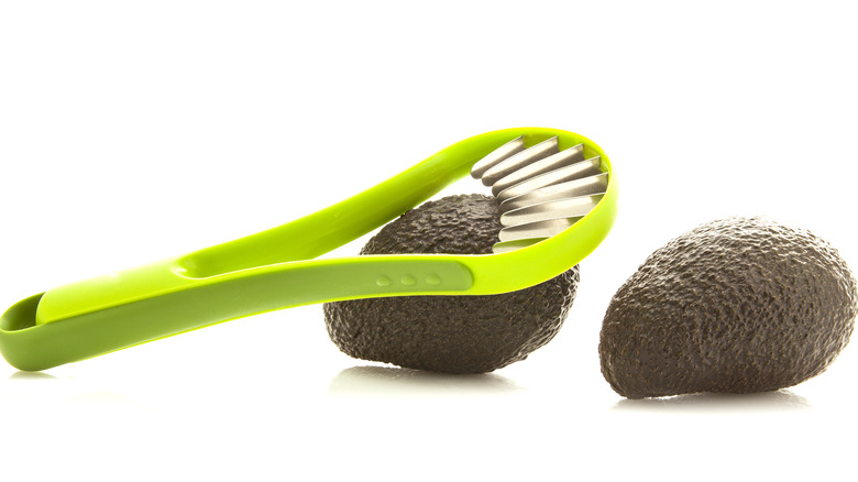 green avocado slicer resting on avocado