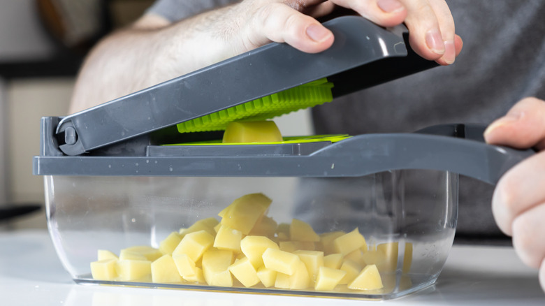 manual chopper being used to chop potatoes