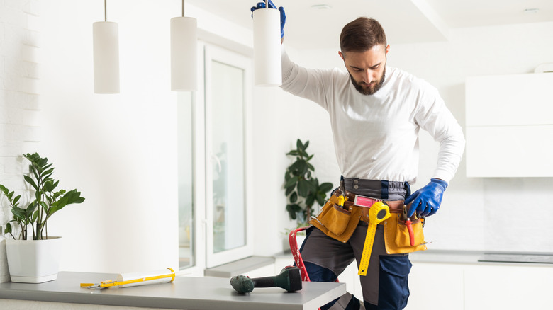 An electrician installing kitchen pendant lights.