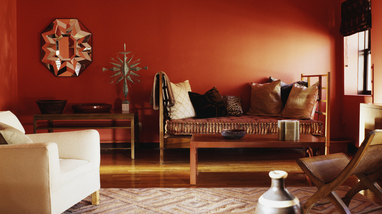 An eclectic living room with dark red walls.