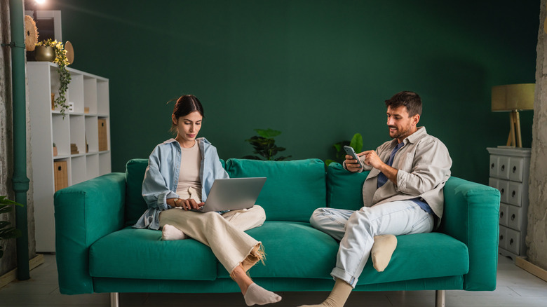A woman and a man sitting on a jade sofa.