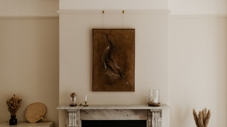 Painting hanging above fireplace on picture rail