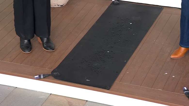 Women standing near a heated mat with melted snow on top