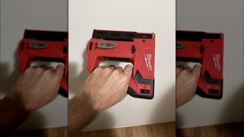 A person holding up Milwaukee's M12 Lithium-Ion Cordless ⅜-inch Crown Stapler