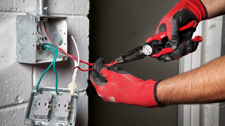 A person using Milwaukee's 9-inch 7-in-1 High Leverage Combination Wire Stripper/Cutter Pliers