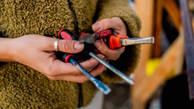 Close-up of a person holding miscellaneous red and black hand tools