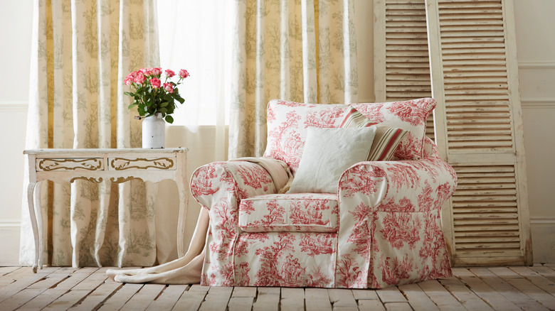 Skirted chair with a red print next to a vintage table