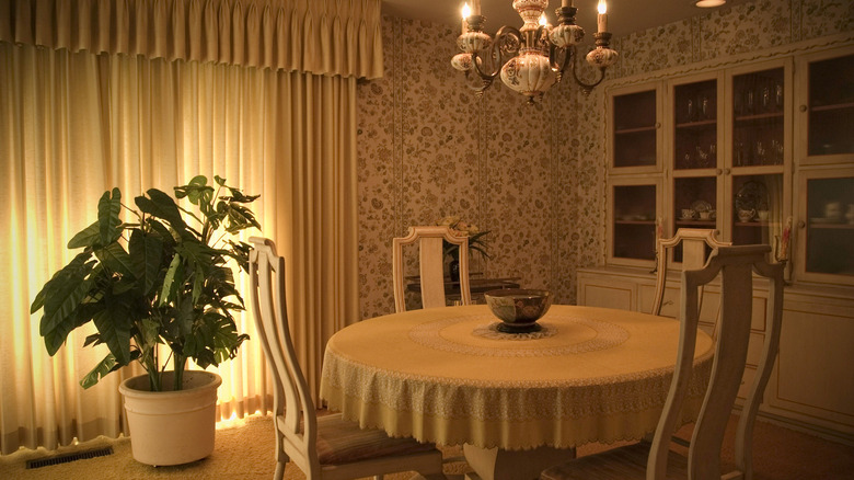 A dining room with white furniture, carpet, and a floral wallpaper