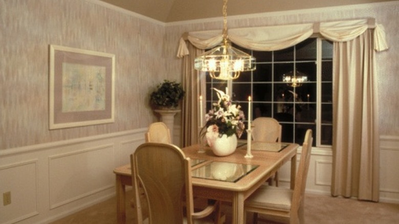 A dining room with a heavy curtain and drapes in a gold color