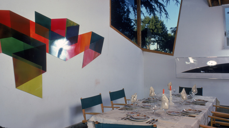 A dining space with director chairs and a plastic geometric wall hanging