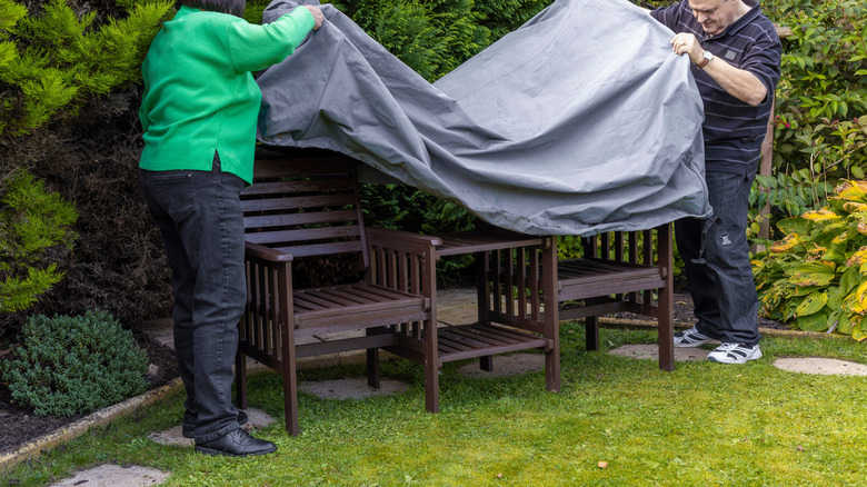 Couple putting a cover on outdoor patio furniture