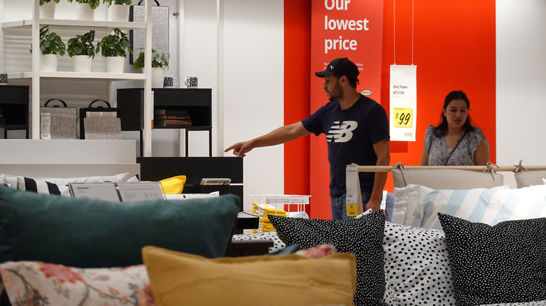 A couple shopping at IKEA with beds in the foreground.