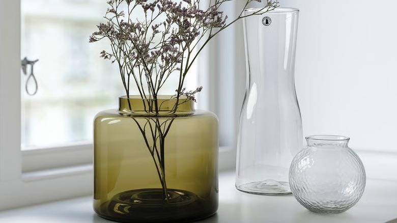 A green glass vase with two clear vases in the background.