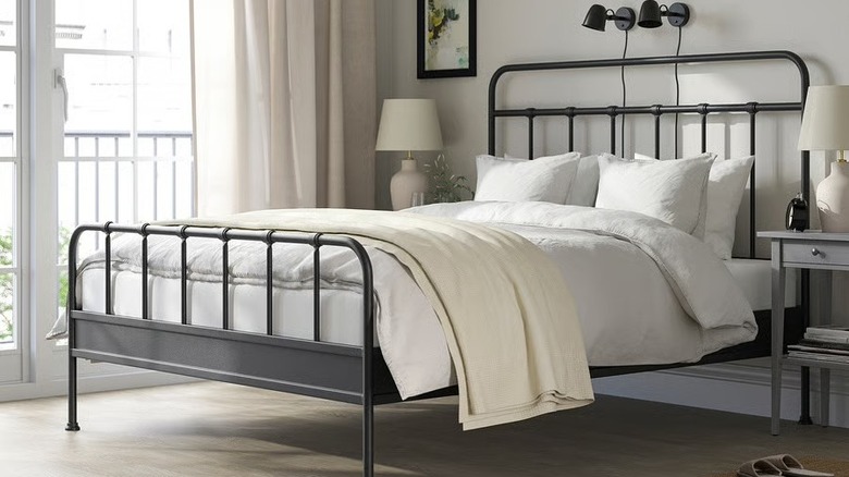 A wrought iron bed frame with white bedding.