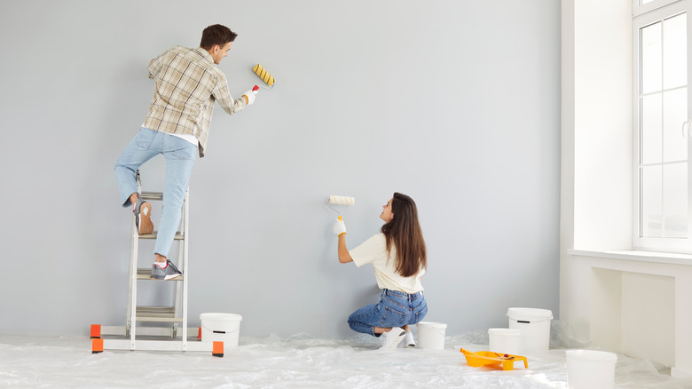 A man and a woman painting the walls of a home