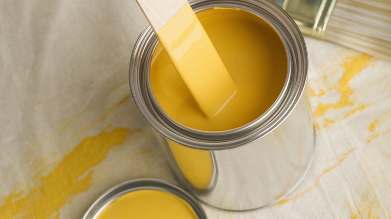 A wooden paint stick inside a can of paint