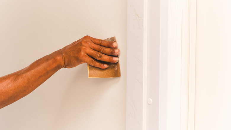 Hand sanding wall with a brown sandpaper