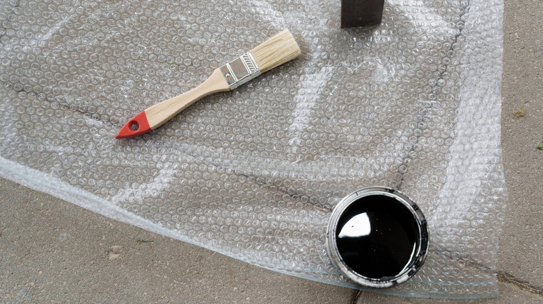 Small paint brush near a can of glossy black paint