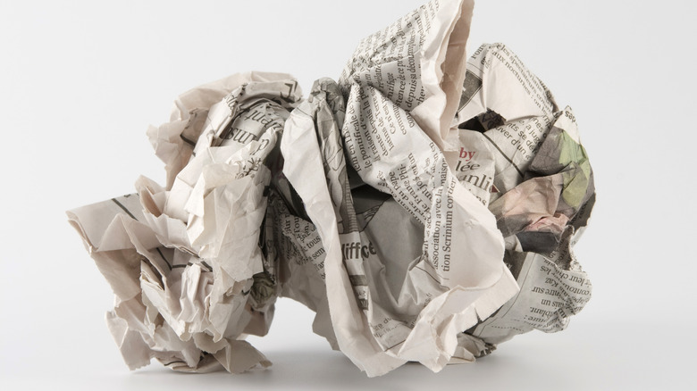 A wad of crumpled newspaper is ready to clean a glass oven door
