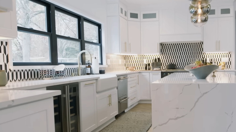 A black and white geometric backsplash in a kitchen with white cabinets and countertops