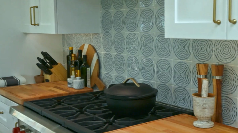 Swirl tile backsplash behind a range with white cabinets