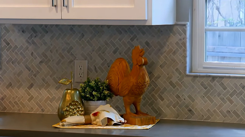 Grey tile laid in a herringbone pattern in the kitchen with decor items on the counter