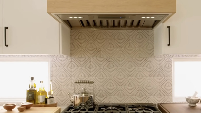 A kitchen range and backsplash with a swirled, textured tile in earthy tones