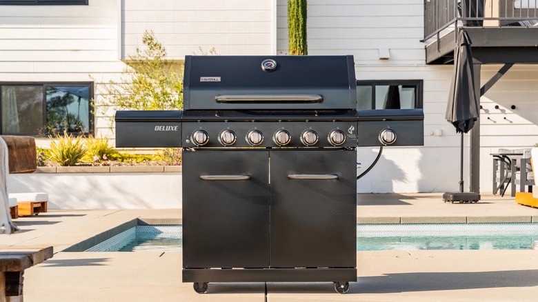 A large black BBQ grill near a pool