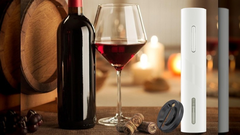 A red electric wine opener near a glass and bottle of red wine